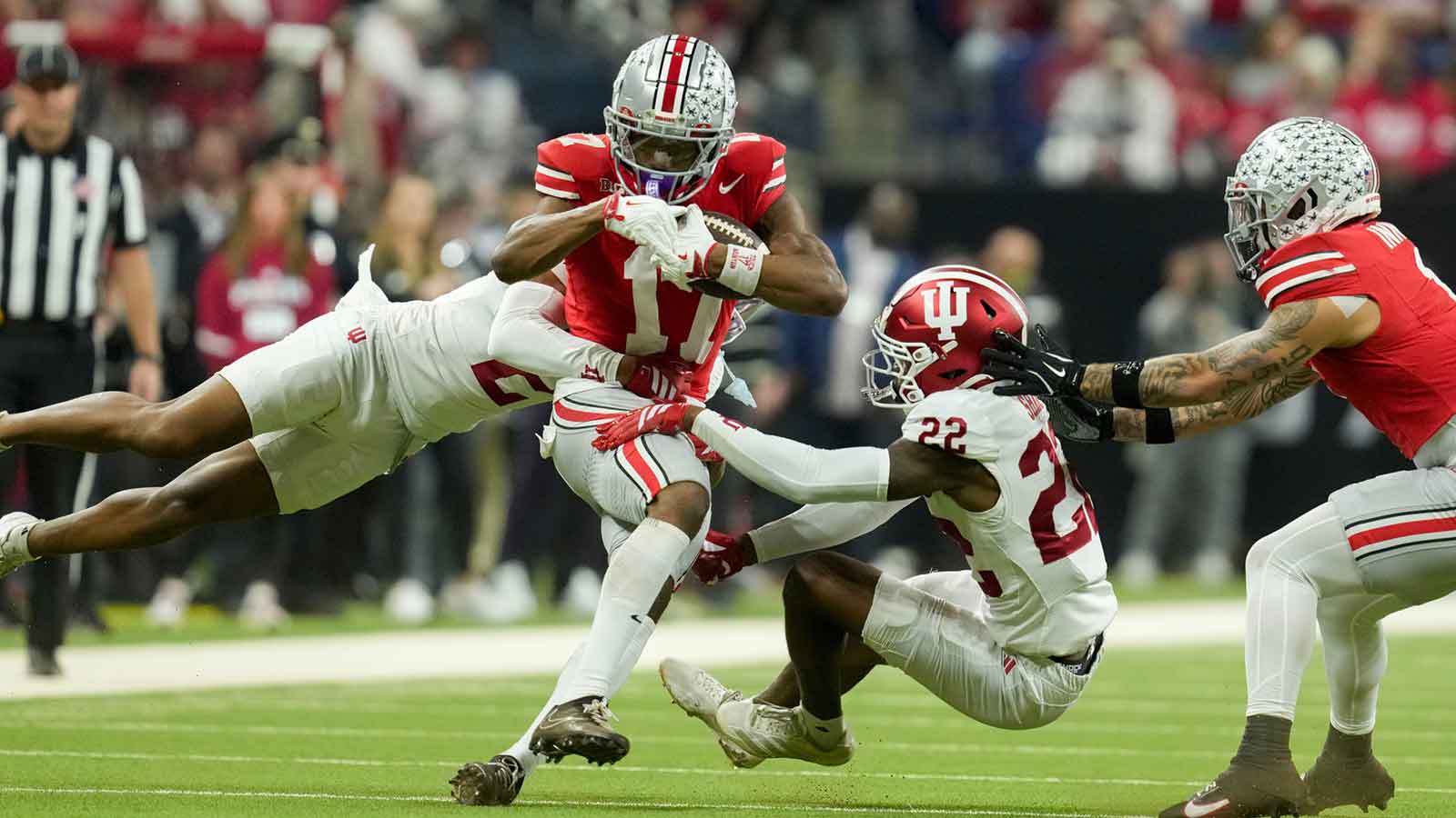 Indiana Hoosiers defensive back Byron Baldwin Jr. (2) and Indiana Hoosiers defensive back Jamari Sharpe (22) bring down Ohio State Buckeyes wide receiver Carnell Tate (17) on Saturday, Dec. 6, 2025, during the Big Ten football championship at Lucas Oil Stadium in Indianapolis.