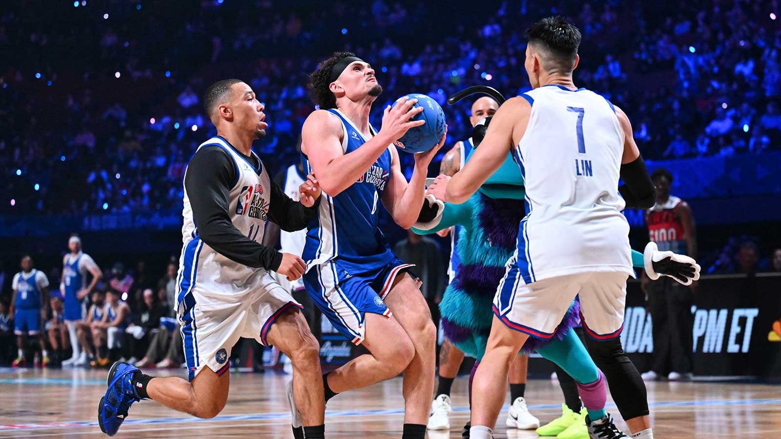 Adrien Nunez of Team 2 drives to the basket as Amon-Ra St. Brown of Team 1 and Jeremy Lin of Team 1 defend during the NBA All Star Celebrity Game at Kia Forum.