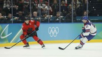 Nathan MacKinnon (29) of Canada in action against Dylan Larkin (21) of the United States in the men's ice hockey gold medal game during the Milano Cortina 2026 Olympic Winter Games at Milano Santagiulia Ice Hockey Arena.