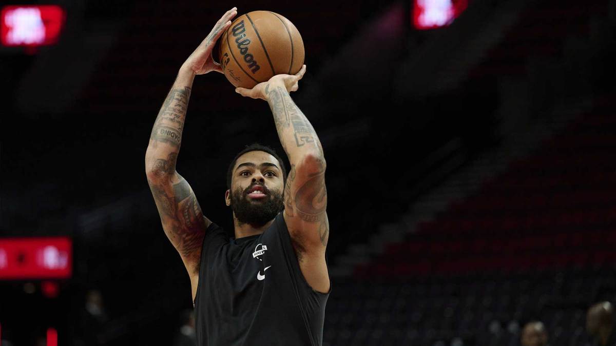 Mavericks guard D'Angelo Russell (5) warms up before a game against the Portland Trail Blazers at Moda Center with the Bucks logo and Marc Stein in the background