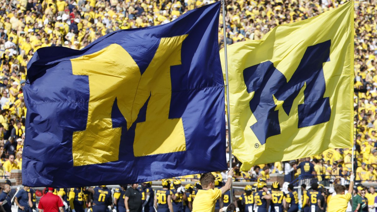 Michigan Wolverines cheerleader run flags down the field before the game against the Wisconsin Badgers at Michigan Stadium.