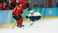 Nathan MacKinnon (29) of Canada looks to pass as Mikko Rantanen (96) of Finland defends during the second period in a men's ice hockey semifinal during the Milano Cortina 2026 Olympic Winter Games at Milano Santagiulia Ice Hockey Arena.