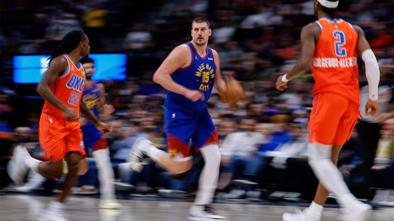 Denver Nuggets center Nikola Jokic (15) dribbles the ball up court against Oklahoma City Thunder guard Cason Wallace (22) and guard Shai Gilgeous-Alexander (2) in the fourth quarter at Ball Arena.