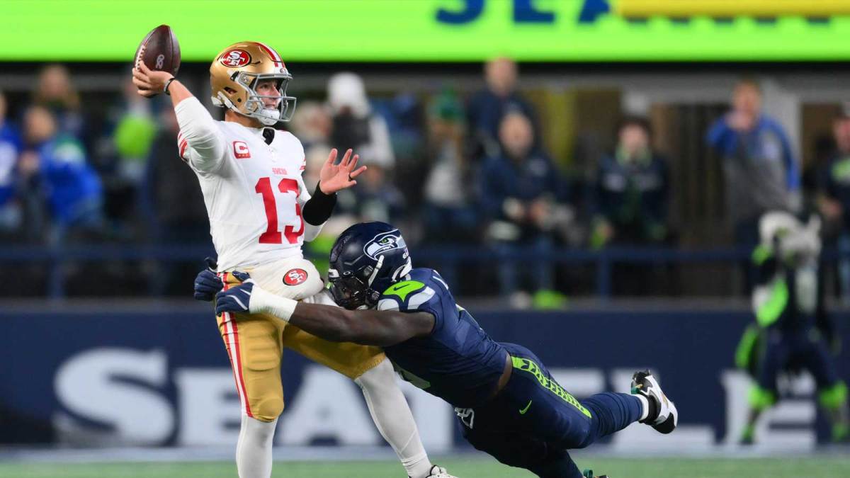 San Francisco 49ers quarterback Brock Purdy (13) is pressured by Seattle Seahawks defensive end DeMarcus Lawrence (0) during the first half in an NFC Divisional Round game at Lumen Field