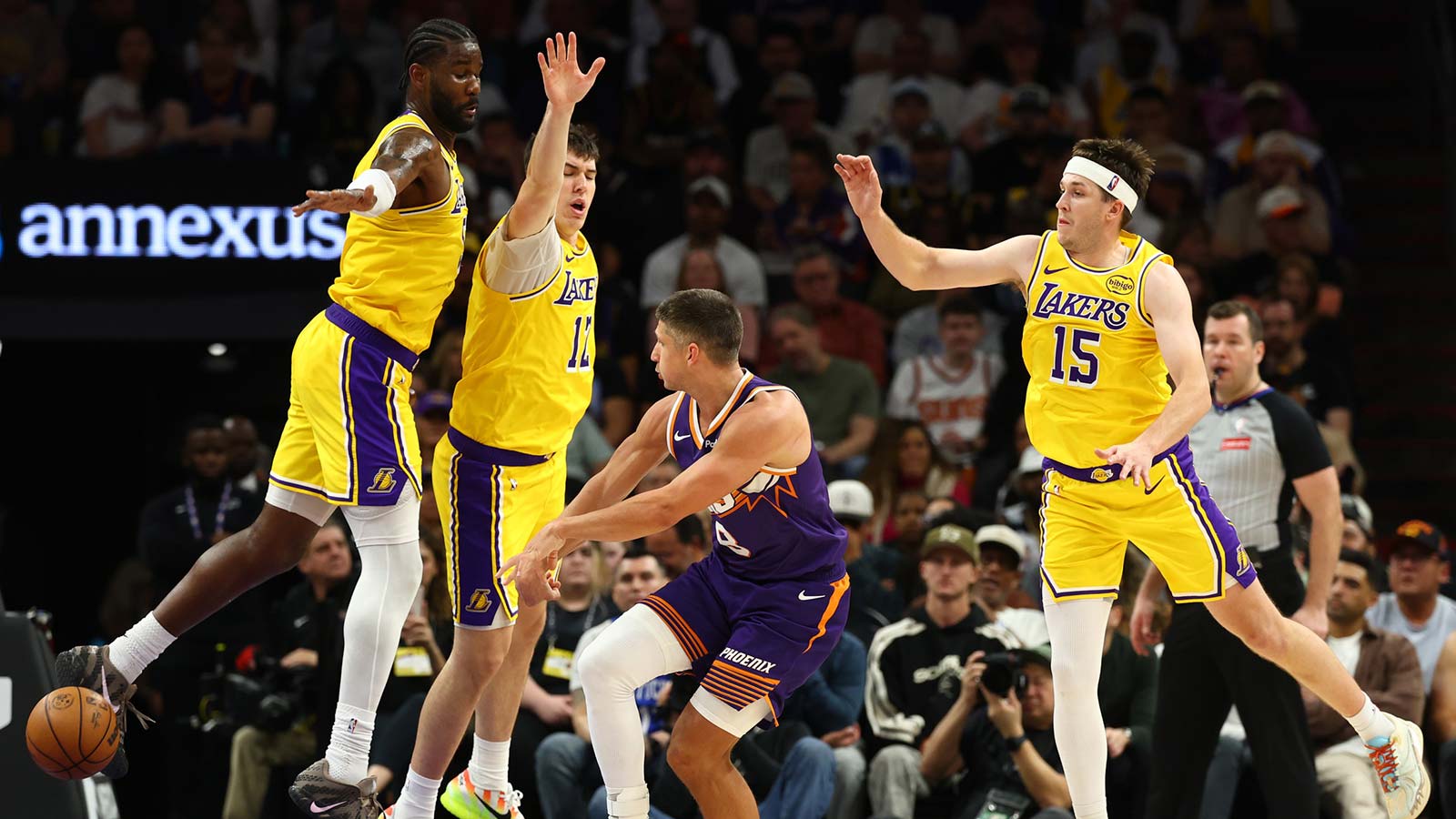 Phoenix Suns guard Grayson Allen (8) passes the ball against Los Angeles Lakers center Deandre Ayton (5), forward Jake LaRavia (12) and guard Austin Reaves (15) in the second half at Mortgage Matchup Center.