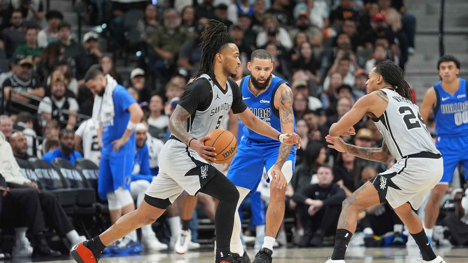 San Antonio Spurs guard Stephon Castle (5) dribbles past Dallas Mavericks forward Caleb Martin (16) in the second half at Frost Bank Center.