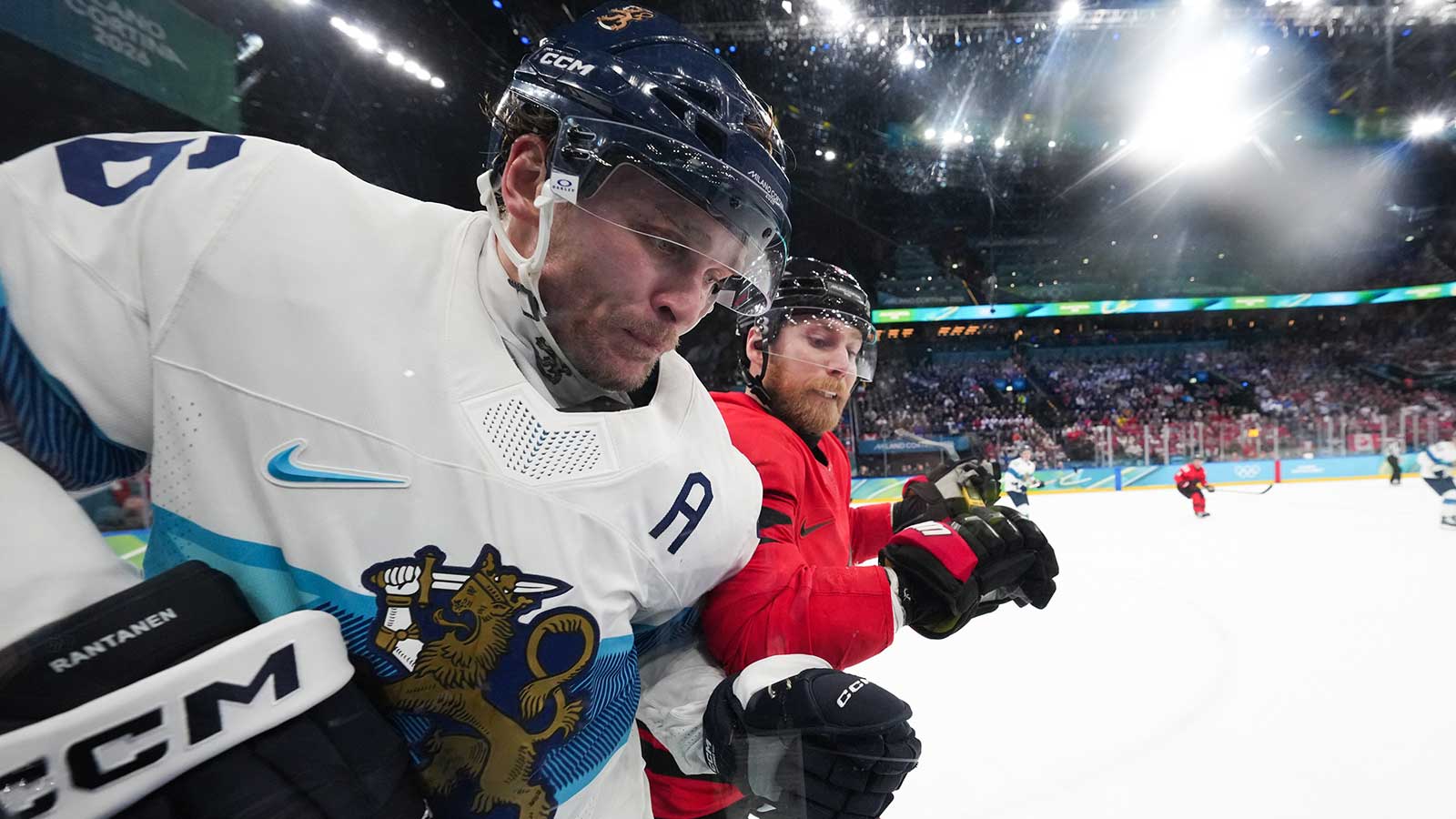 Sam Bennett (9) of Canada checks Mikko Rantanen (96) of Finland into the boards during the second period in a men's ice hockey semifinal during the Milano Cortina 2026 Olympic Winter Games at Milano Santagiulia Ice Hockey Arena