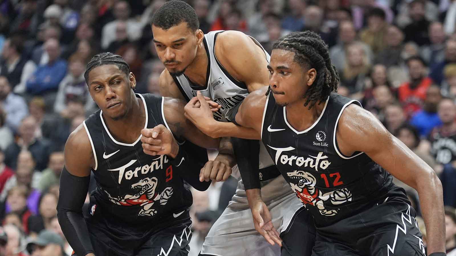 Toronto Raptors forward RJ Barrett (9) and forward Collin Murray-Boyles (12) block out San Antonio Spurs center Victor Wembanyama (1) during the first half at Scotiabank Arena.