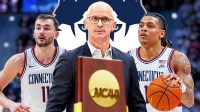 Solo Ball, Dan Hurley, and Alex Karaban with the NCAA championship trophy in the foreground and UConn logo in the background.