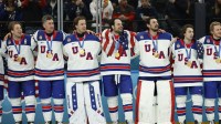 United States players including Auston Matthews (34) of the United States and Connor Hellebuyck (37) of the United States celebrate with their gold medals after defeating Canada in the men's ice hockey gold medal game during the Milano Cortina 2026 Olympic Winter Games at Milano Santagiulia Ice Hockey Arena.