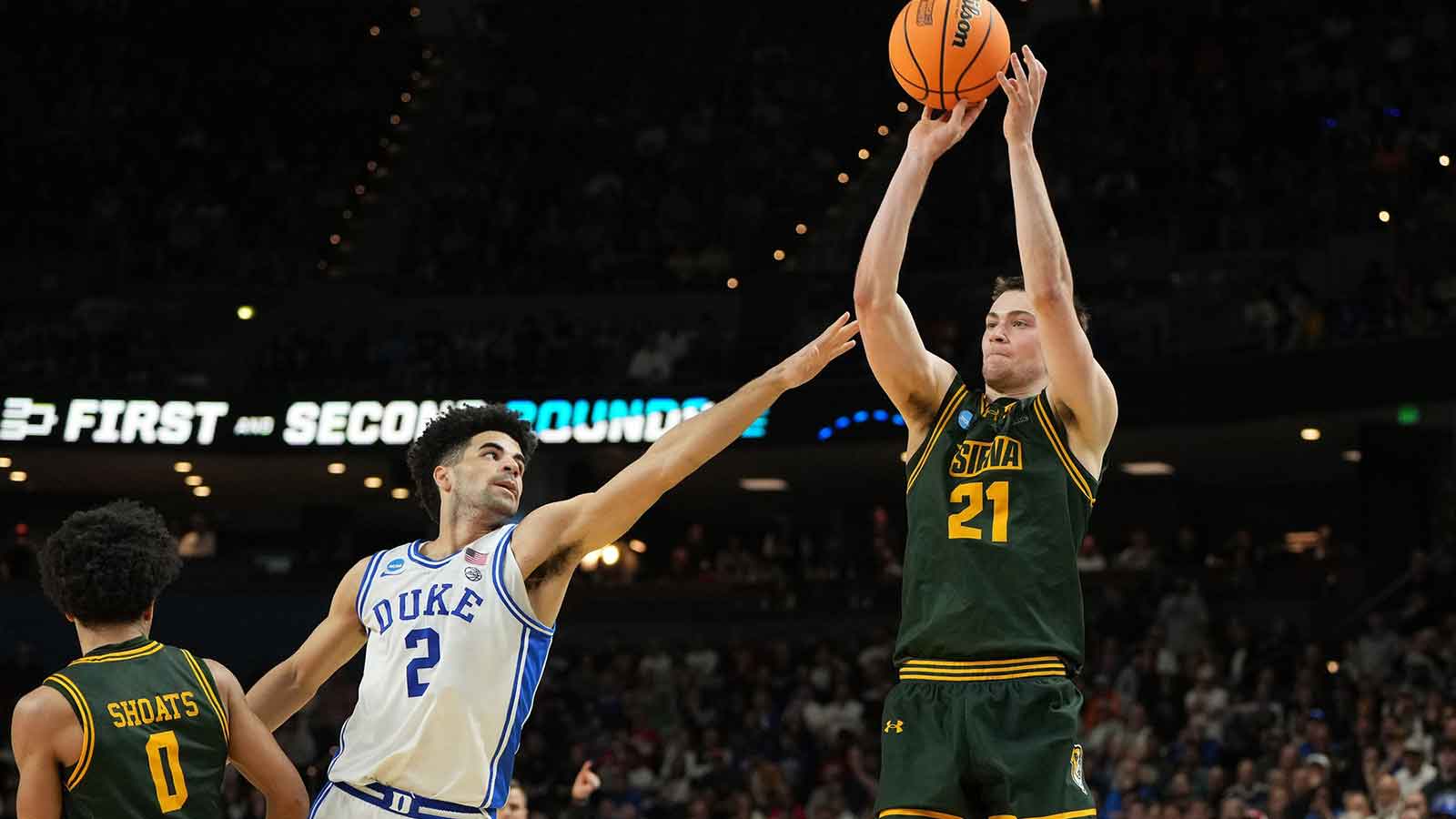 Siena Saints forward Brendan Coyle (21) shoots the ball over Duke Blue Devils guard Cayden Boozer (2) in the second half during a first round game of the men's 2026 NCAA Tournament at Bon Secours Wellness Arena.