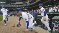 Chicago Cubs center fielder Pete Crow-Armstrong (4) grabs dirt as he enters the field with teammates for an Opening Day game against the Washington Nationals at Wrigley Field.