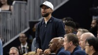 Golden State Warriors guard Stephen Curry (in white baseball hat) cheers on his team against the Los Angeles Clippers during the second quarter at Chase Center.