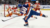 New York Islanders defenseman Matthew Schaefer (48) attempts a shot and Calgary Flames goaltender Dustin Wolf (32) makes a the save during the second period at UBS Arena.