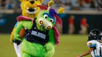 Orlando Magic mascot Stuff the Magic Dragon runs against a child football player during halftime between the Jacksonville Jaguars and the Philadelphia Eagles during the second quarter at TIAA Bank Field.