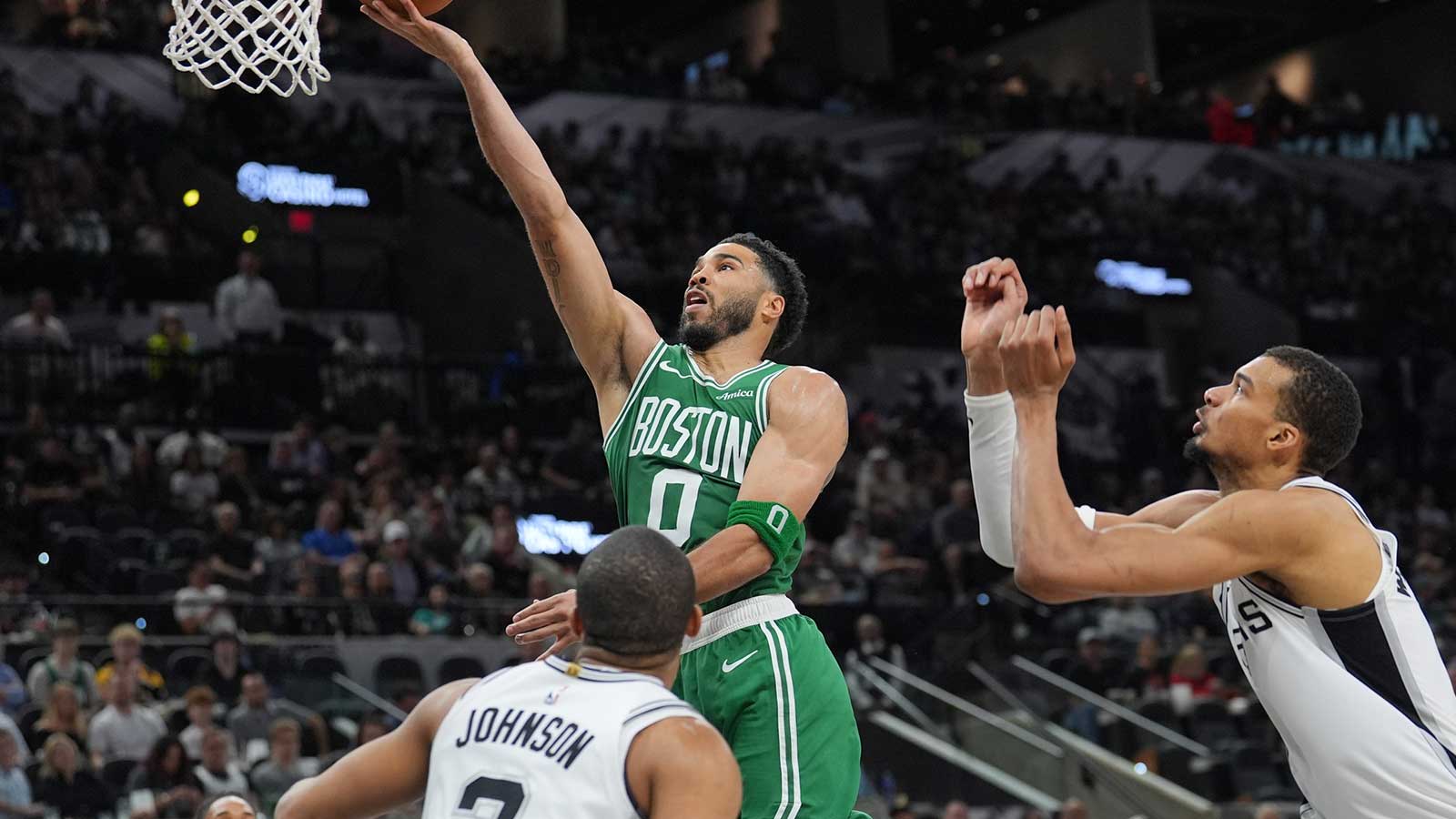 Boston Celtics forward Jayson Tatum (0) shoots the ball against San Antonio Spurs forwards Keldon Johnson (3) and Victor Wembanyama (1) in the second half at Frost Bank Center.