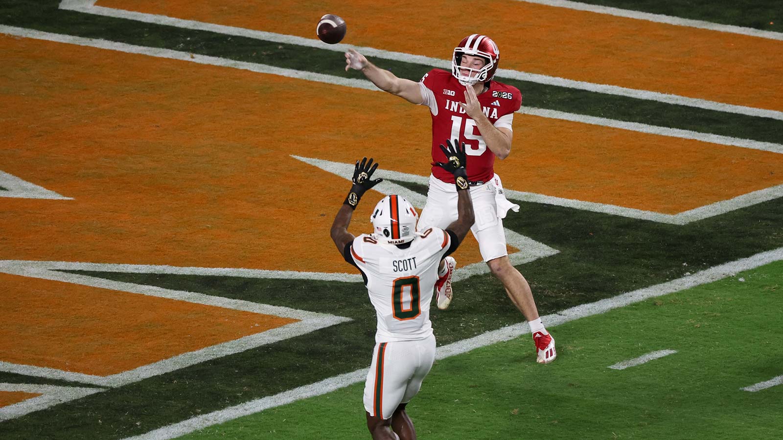Indiana Hoosiers quarterback Fernando Mendoza (15) passes the ball under pressure by Miami Hurricanes defensive back Keionte Scott (0) in the first quarter during the College Football Playoff National Championship game at Hard Rock Stadium.