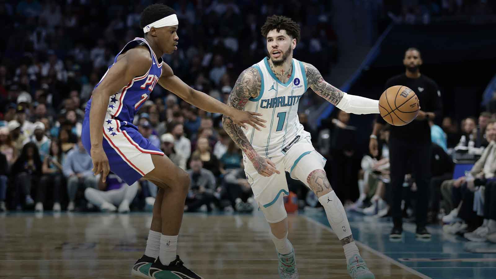 Charlotte Hornets guard LaMelo Ball (1) tries to drive past Philadelphia 76ers guard V.J. Edgecombe (77) during the fourth quarter at Spectrum Center.