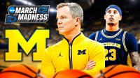 Michigan HC Dusty May (center) with Michigan SF Yaxel Lendeborg. Michigan Wolverines logo and March Madness logo behind them