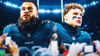 Marcus Epps (No. 39) and Ashtyn Davis (No. 21) in Eagles uniforms in front of the team's stadium.