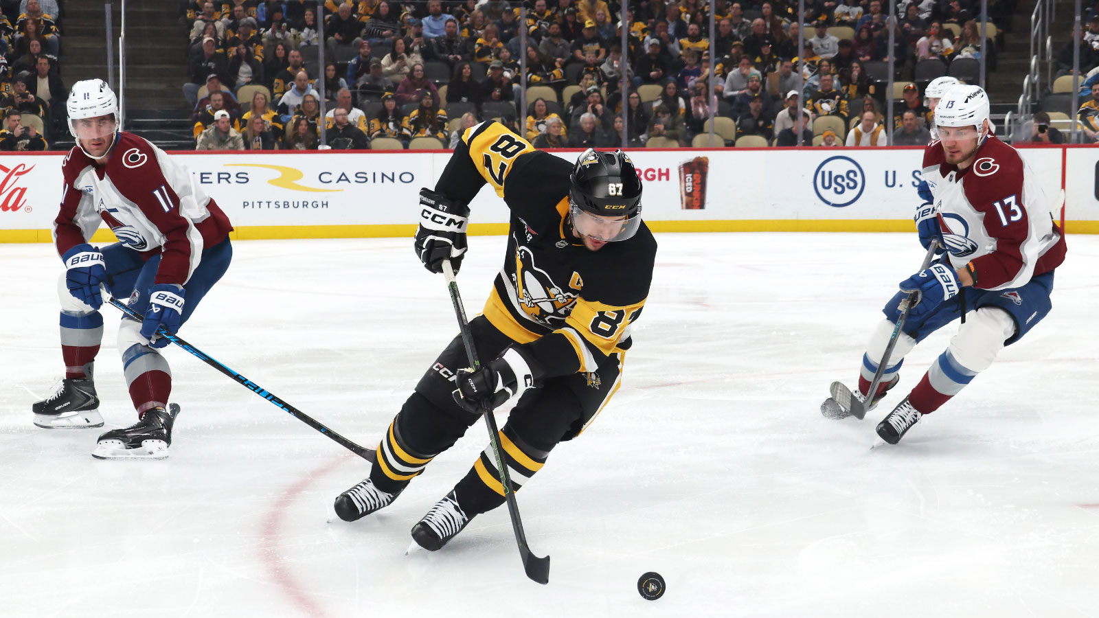 Pittsburgh Penguins center Sidney Crosby (87) moves the puck against Colorado Avalanche center Brock Nelson (11) and right wing Valeri Nichushkin (13) during the third period t PPG Paints Arena.