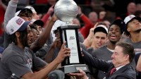 St. John's Red Storm head coach Rick Pitino hands the trophy to forward Zuby Ejiofor (24) after defeating the Connecticut Huskies to win the men's Big East Conference Tournament Championship game at Madison Square Garden.