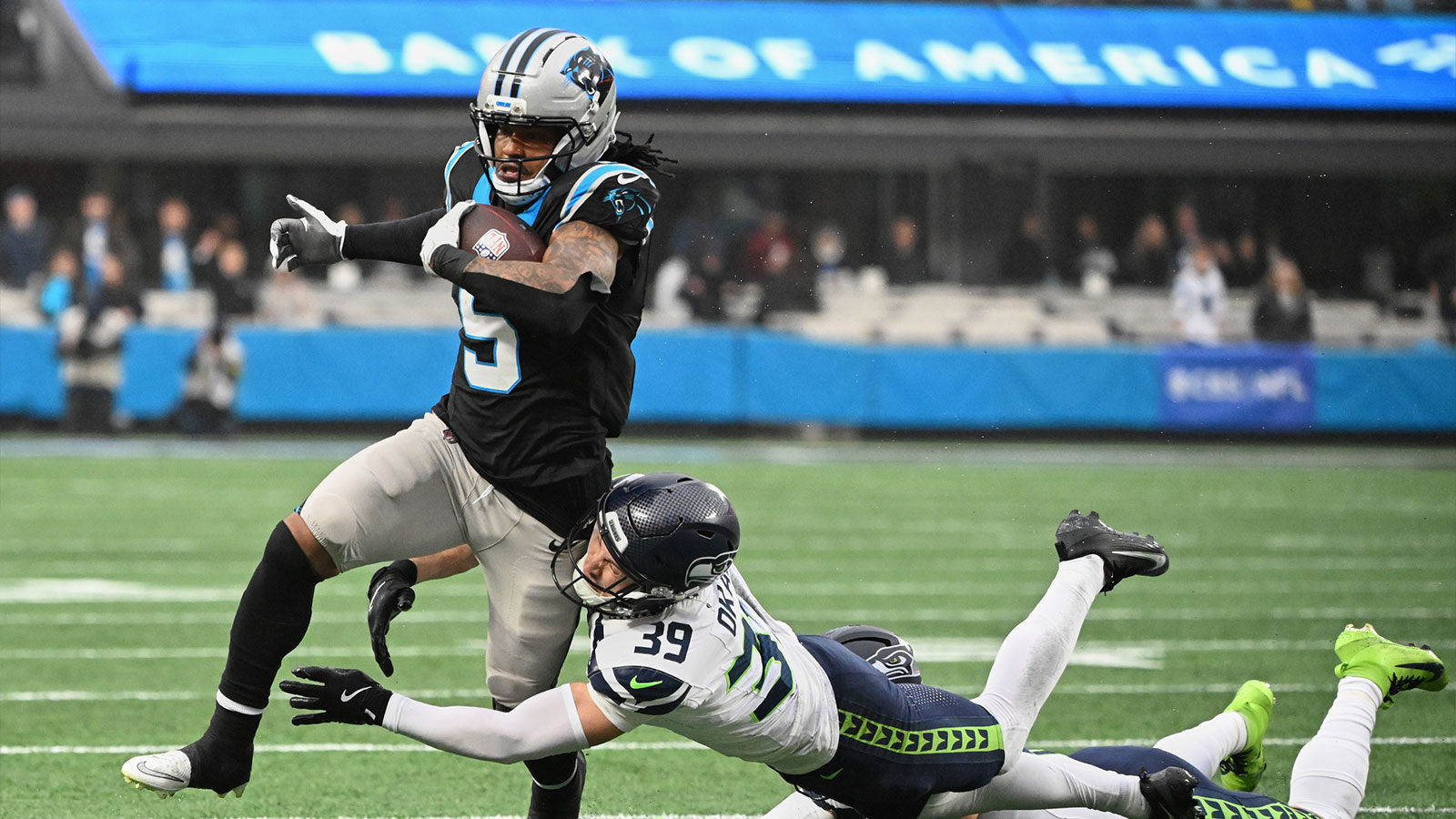 Carolina Panthers running back Rico Dowdle (5) runs the ball against Seattle Seahawks safety Ty Okada (39) and linebacker Drake Thomas (42) (obscured) during the second quarter at Bank of America Stadium. 