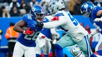 New York Giants running back Devin Singletary (26) tries to run past Dallas Cowboys defensive end Sam Williams (54), Sunday, January 4, 2026, in East Rutherford.