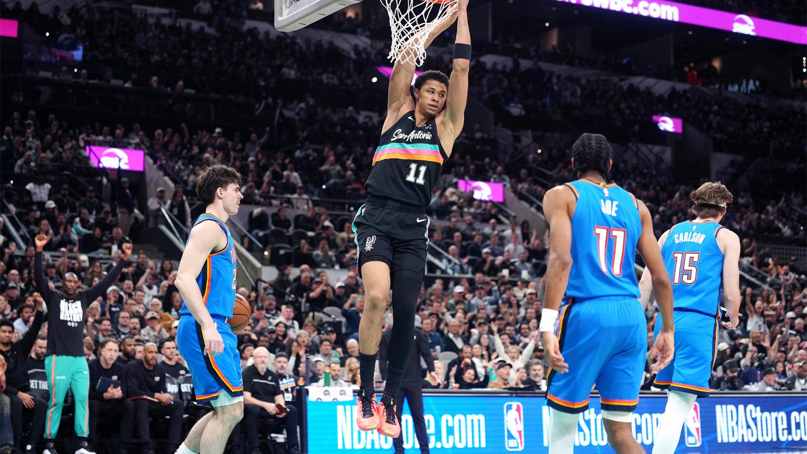 San Antonio Spurs forward Carter Bryant (11) hangs on to the rim after dunking over Oklahoma City Thunder