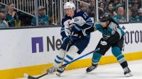 San Jose Sharks left wing Kiefer Sherwood (44) and Winnipeg Jets defenseman Elias Salomonsson (57) battle for the puck against the boards during the second period at SAP Center at San Jose.