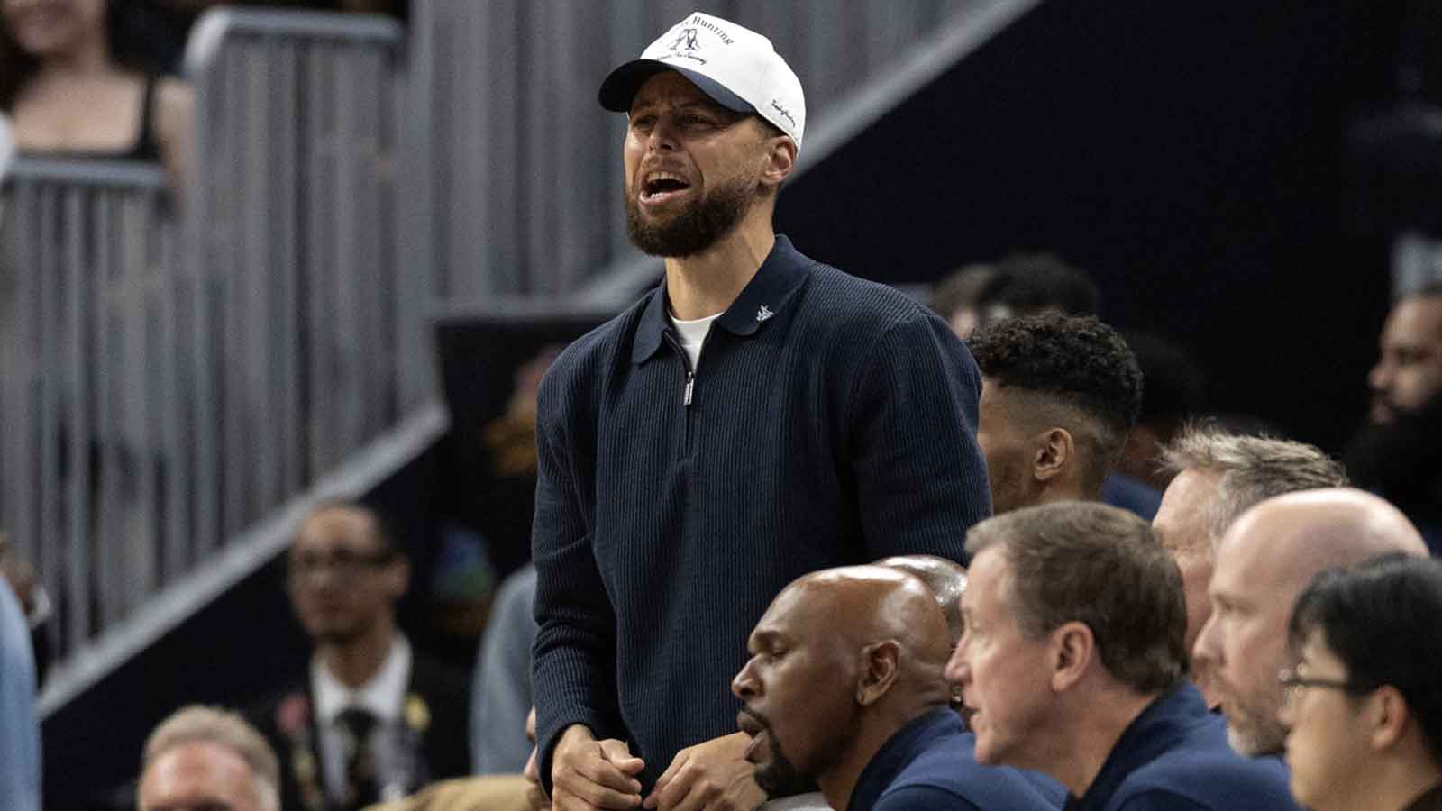 Golden State Warriors guard Stephen Curry (in white baseball hat) cheers on his team against the Los Angeles Clippers during the second quarter at Chase Center.