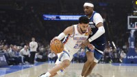 Thunder guard Ajay Mitchell (25) drives to the basket against Minnesota Timberwolves guard Bones Hyland (8) during the first half at Paycom Center with Thunder coach Mark Daigneault in the background