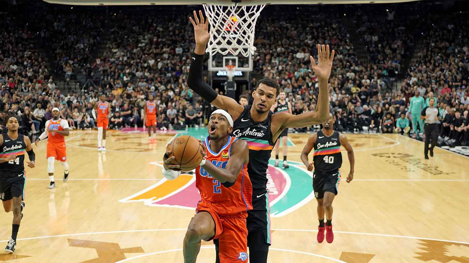 Thunder guard Shai Gilgeous-Alexander (2) drives to the basket past San Antonio Spurs forward Victor Wembanyama (1) during the first half at Frost Bank Center