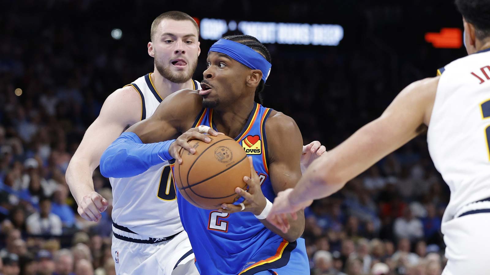 Thunder guard Shai Gilgeous-Alexander (2) drives between Denver Nuggets guard Christian Braun (0) and forward Spencer Jones (21) during the second half at Paycom Center
