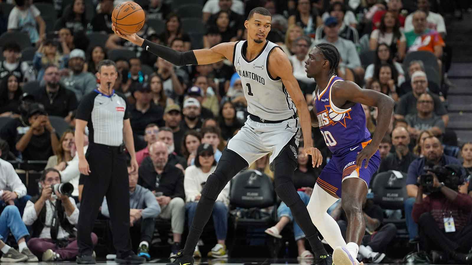 San Antonio Spurs forward Victor Wembanyama (1) keeps the ball from Phoenix Suns forward Rasheer Fleming (20) in the first half at Frost Bank Center.