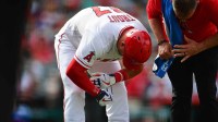 Angels center fielder Mike Trout (27) has his hand checked by trainer