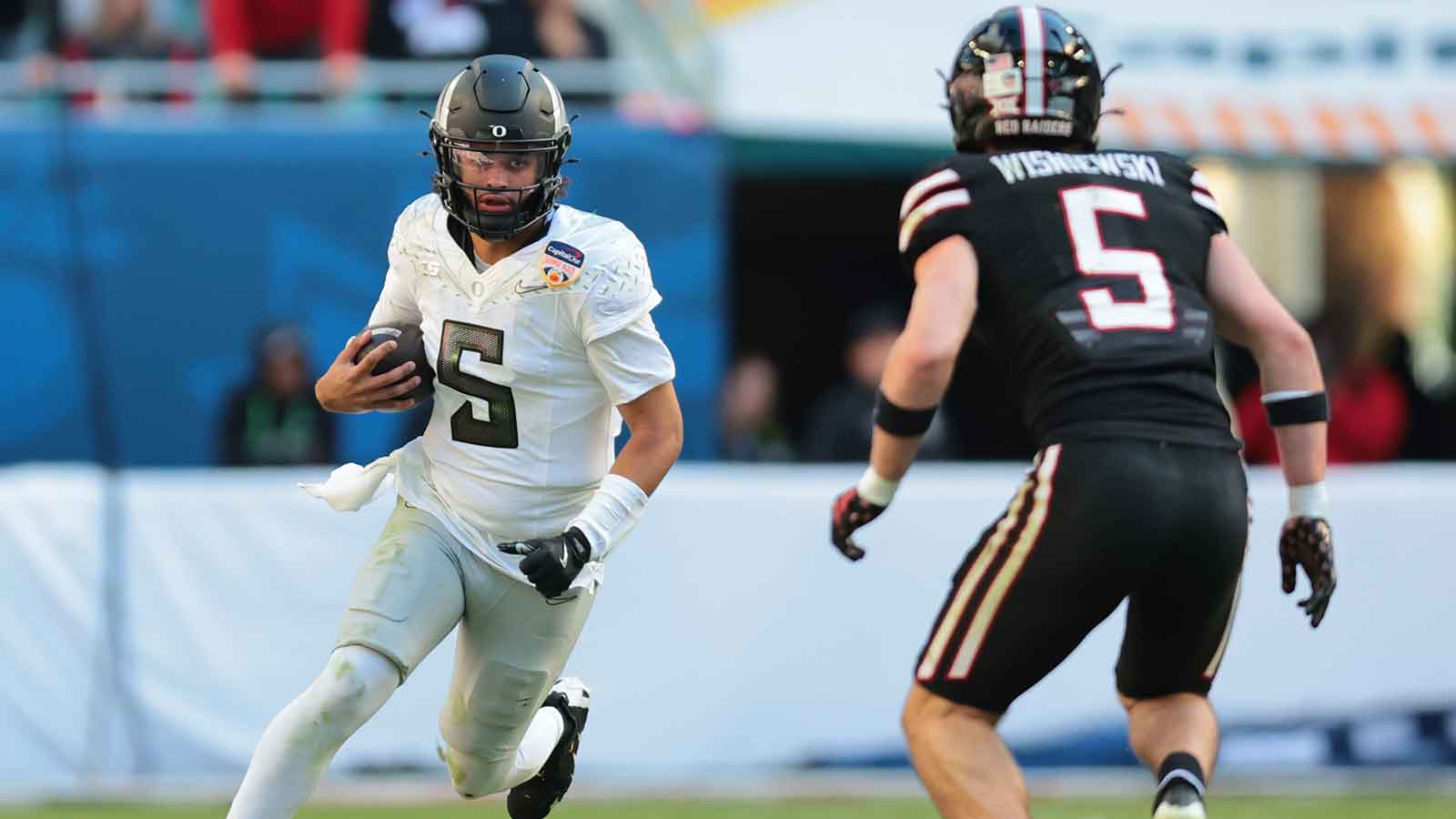 Oregon Ducks quarterback Dante Moore (5) carries the ball as Texas Tech Red Raiders defensive back Cole Wisniewski (5) defends during the second half of the 2025 Orange Bowl and quarterfinal game of the College Football Playoff at Hard Rock Stadium. 