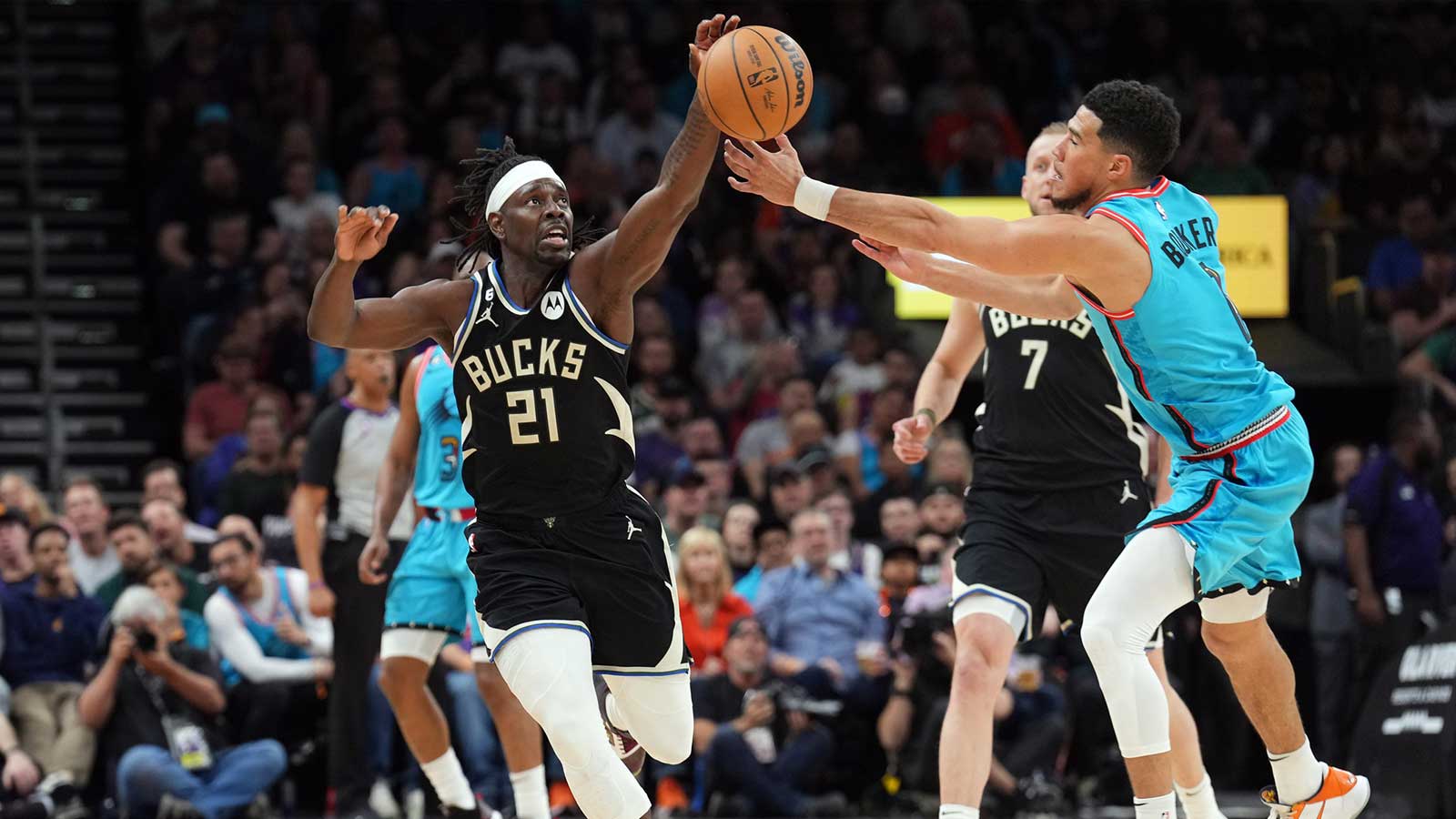 Milwaukee Bucks guard Jrue Holiday (21) and Phoenix Suns guard Devin Booker (1) go after a loose ball during the second half at Footprint Center.