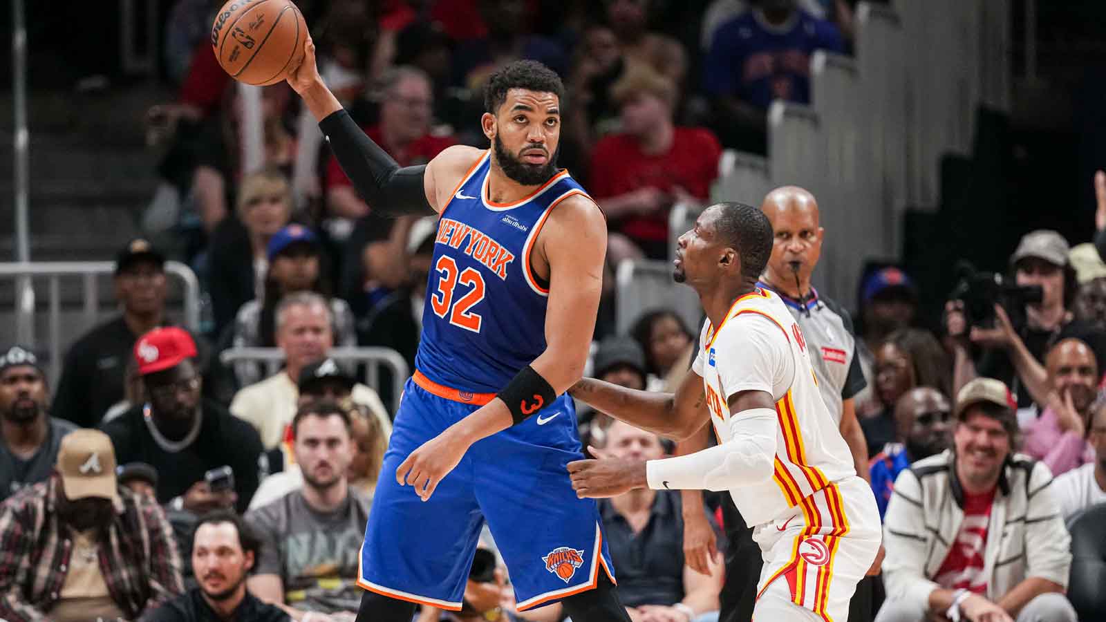 New York Knicks center Karl-Anthony Towns (32) holds the ball away from Atlanta Hawks forward Jonathan Kuminga (0) during the second half during game four of the first round of the 2026 NBA Playoffs at State Farm Arena. 