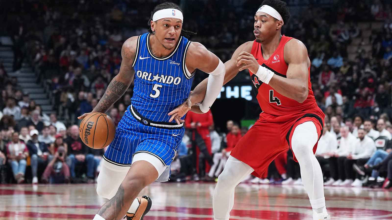 Orlando Magic forward Paolo Banchero (5) controls the ball as Toronto Raptors forward Scottie Barnes (4) tries to defend during the first quarter at Scotiabank Arena.