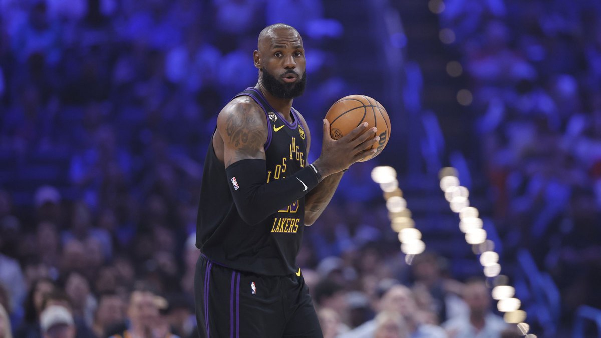 Lakers forward LeBron James (23) moves the ball down the court against the Oklahoma City Thunder during the first quarter at Paycom Center with Lakers' Luka Doncic and Austin Reaves, and Skip Bayless in the background