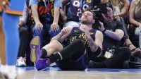 Lakers guard Luka Doncic (77) falls to the court during a play against the Oklahoma City Thunder during the third quarter at Paycom Center with ESPN's Stephen A Smith in the background