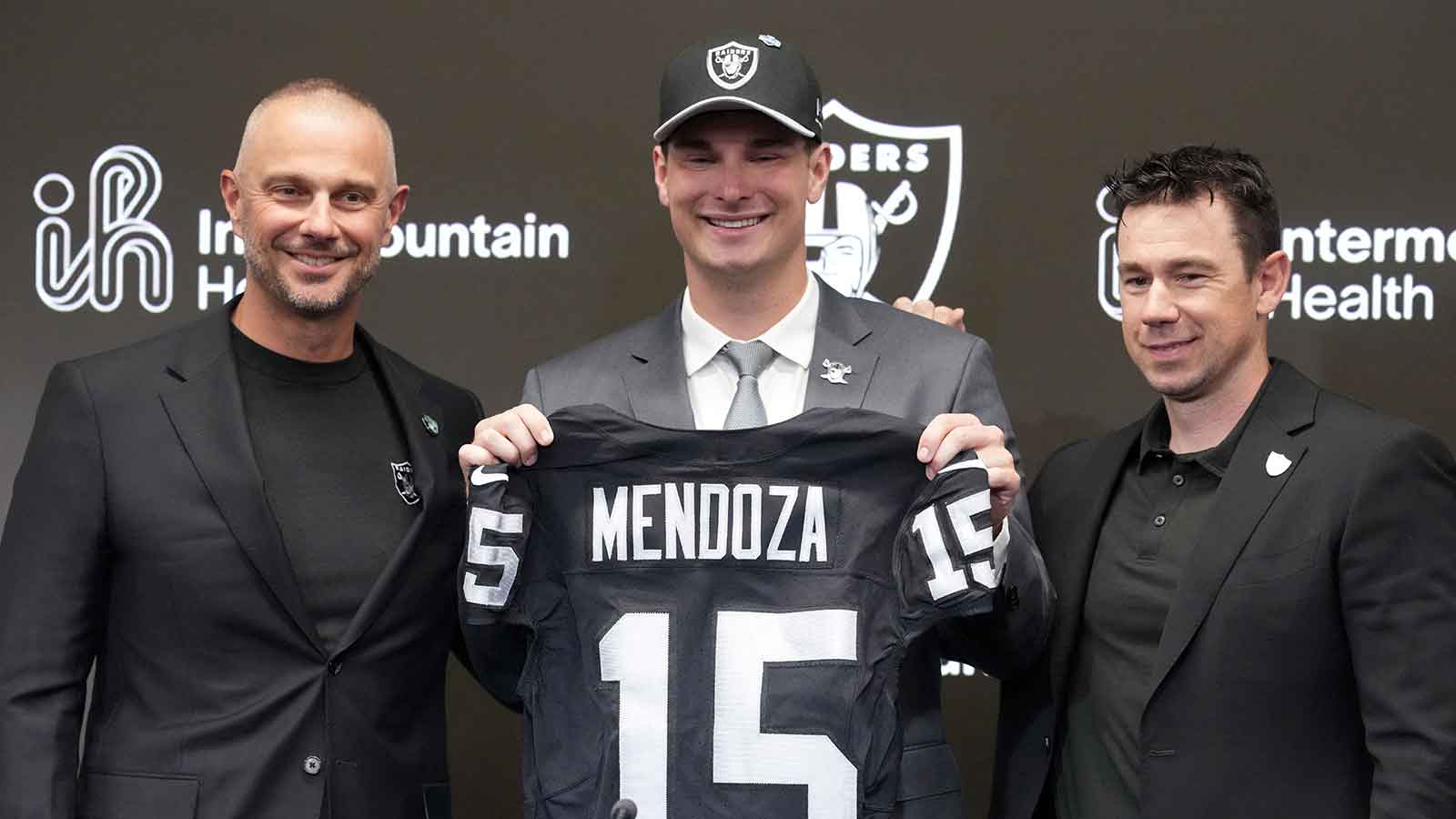 Las Vegas Raiders quarterback Fernando Mendoza (center) poses with jersey at introductory press conference at Intermountain Health Performance Center flanked by general manager John Spytek (left) and head coach Klint Kubiak after being selected as the No. 1 pick in the 2026 NFL Draft. 