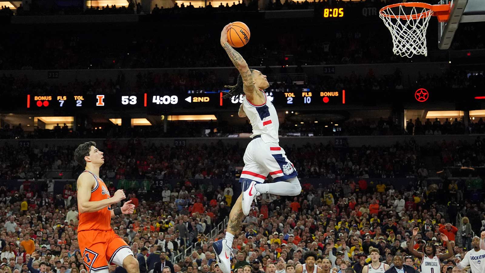 UConn Huskies guard Solo Ball (1) dunks against the Illinois Fighting Illini during the second half of a semifinal of the Final Four of the men's 2026 NCAA Tournament at Lucas Oil Stadium.