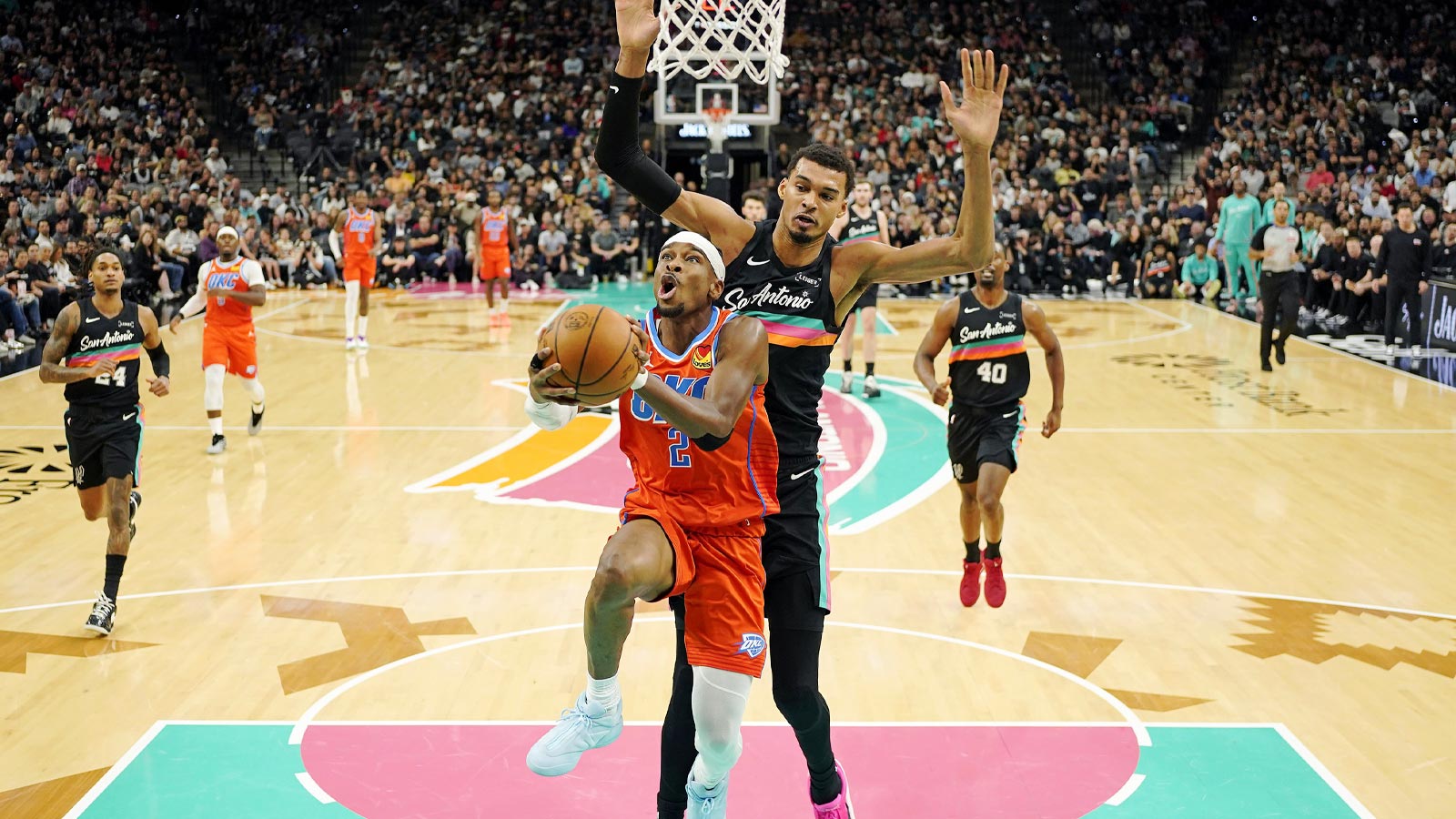 Thunder guard Shai Gilgeous-Alexander (2) drives to the basket past San Antonio Spurs forward Victor Wembanyama (1) during the first half at Frost Bank Center