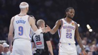 Thunder guard Cason Wallace (22) and guard Alex Caruso (9) high five after a play against the Milwaukee Bucks during the first half at Paycom Center with All-Defensive Team logo in the background