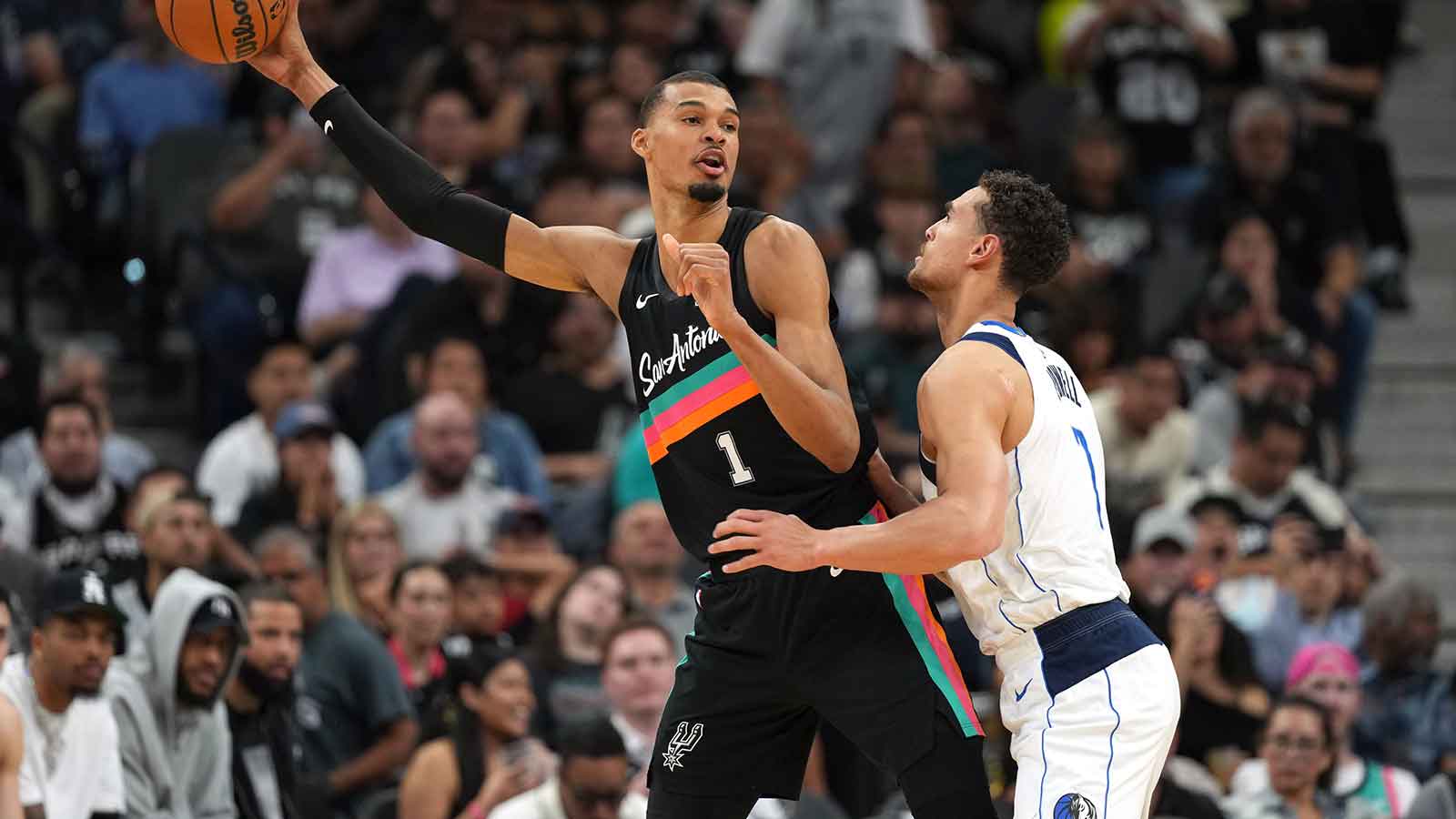 San Antonio Spurs forward Victor Wembanyama (1) looks to pass the ball while defended by Dallas Mavericks forward Dwight Powell (7) during the second half at Frost Bank Center.