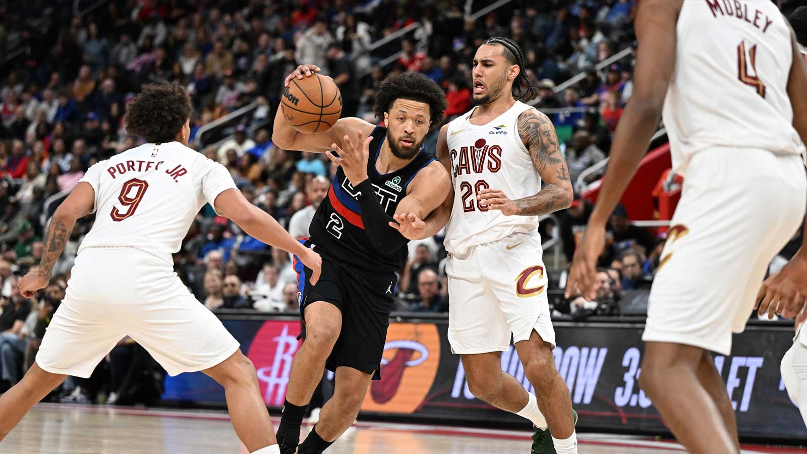Detroit Pistons guard Cade Cunningham (2) tries to drive between Cleveland Cavaliers guard Craig Porter Jr. (9) and Cleveland Cavaliers guard Jaylon Tyson (20) in the first half at Little Caesars Arena.