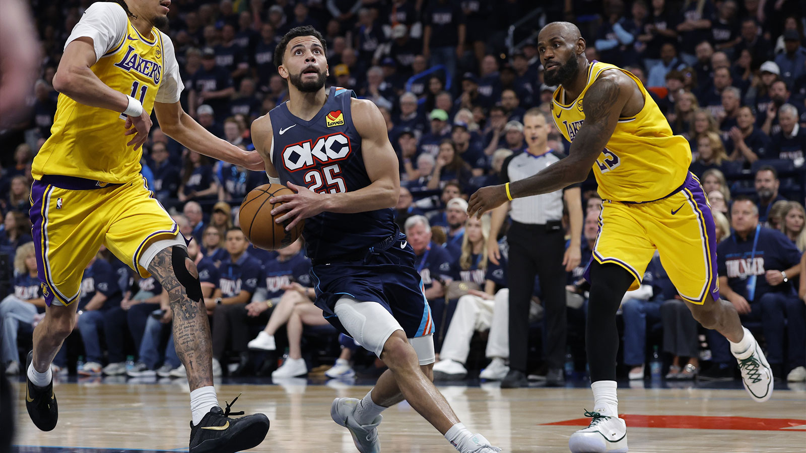 Thunder guard Ajay Mitchell (25) drives between Los Angeles Lakers center Jaxson Hayes (11) and forward LeBron James (23) in the second half during game two of the second round of the 2026 NBA Playoffs at Paycom Center
