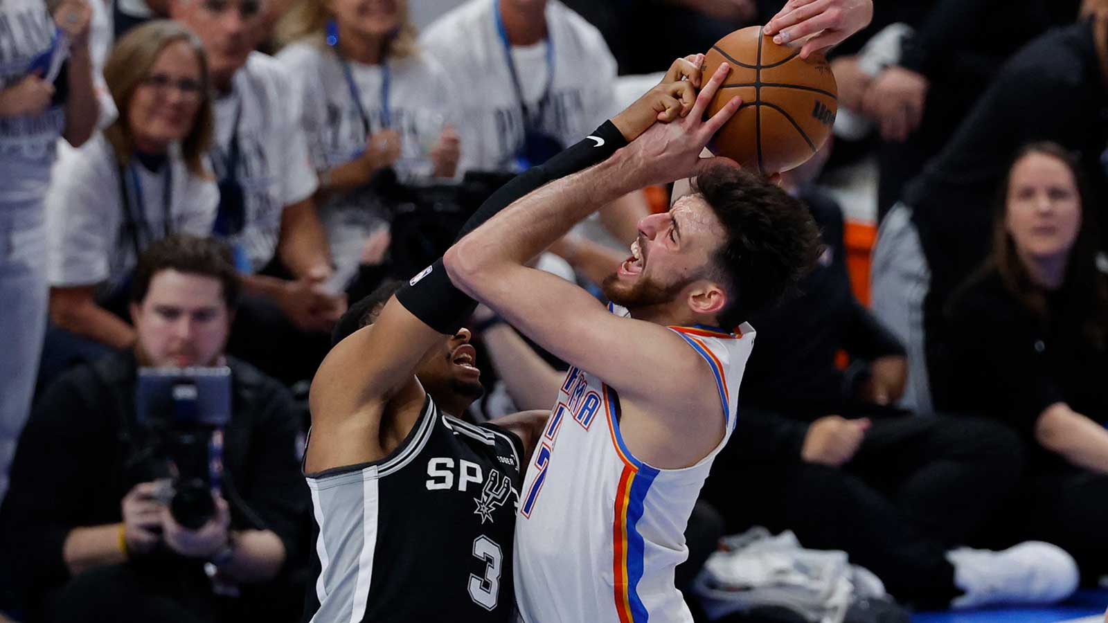 Spurs forward Keldon Johnson (3) blocks Oklahoma City Thunder center Chet Holmgren (7) during the fourth quarter in game five of the western conference finals for the 2026 NBA playoffs at Paycom Center
